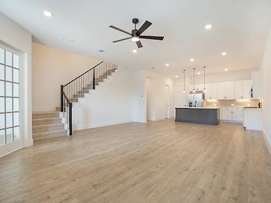 Bright and open living room with wood-style floors, modern lighting, and a stylish ceiling fan — perfect for entertaining.