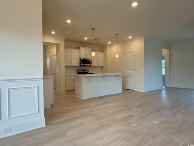 Kitchen with appliances with stainless steel finishes, crown molding, an island with sink, white cabinetry, and recessed lighting