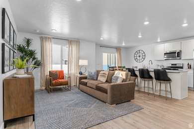 Living area featuring light wood-type flooring, plenty of natural light, recessed lighting, and a textured ceiling