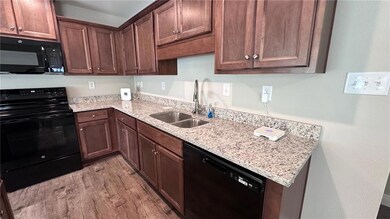 Kitchen featuring black appliances, a sink, light 