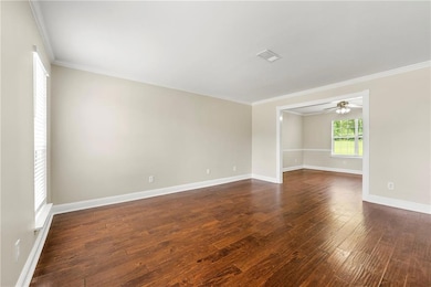 Spare room with dark wood-style flooring, ornamental molding, and ceiling fan