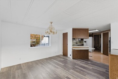 Kitchen with light countertops, light wood-style flooring, a peninsula, a chandelier, and white fridge with ice dispenser