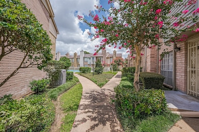 Charming brick townhouse with a landscaped pathway, vibrant flowering trees, and well-maintained shrubs. Ideal for a serene, community-oriented living.