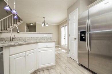 Kitchen featuring stainless steel fridge, a sink, light wood-style floors, a chandelier, and white cabinetry