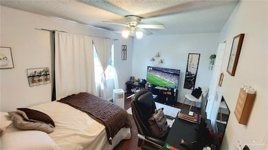 Bedroom featuring wood finished floors, a textured ceiling, and ceiling fan