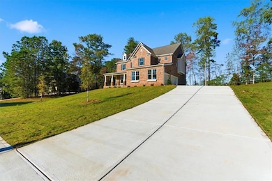 View of front of property featuring a front lawn, a porch, concrete driveway, and brick siding