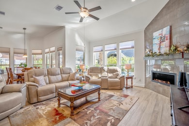 This inviting living area features abundant natural light, a cozy gas fireplace, and comfortable seating with a modern open layout. The dining area is visible in the background, enhancing the spacious feel.