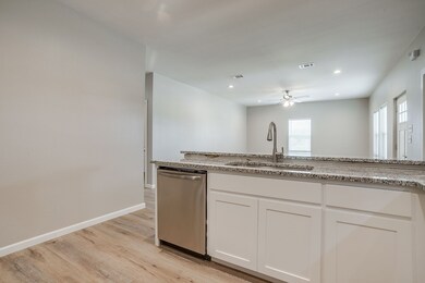 Kitchen featuring white cabinets, dishwasher, light wood finished floors, recessed lighting, and light stone counters