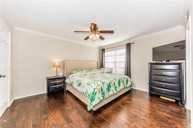 Spacious master bedroom with wood floors and crown