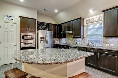 Huge granite island, stainless steel appliances, and ample, richly-stained cabinetry and built-in wine rack.