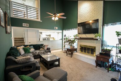 Living room with a fireplace, ceiling fan, brick w