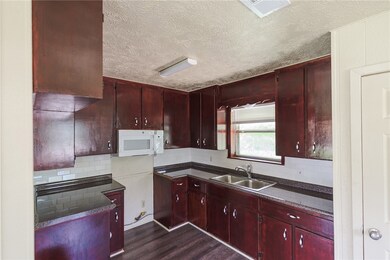 Kitchen with a textured ceiling, reddish brown cab