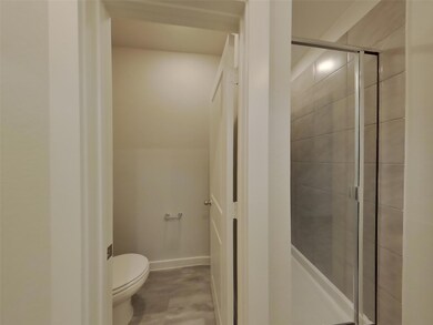 Full bath with toilet, a shower stall, and basebo