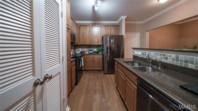 Kitchen featuring ornamental molding, backsplash, black appliances, dark stone countertops, and dark wood-type flooring