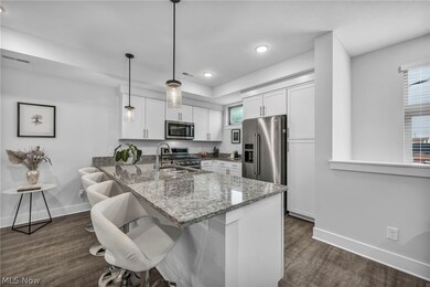 Kitchen with pendant lighting, kitchen peninsula, stainless steel appliances, and white cabinetry