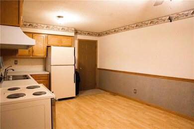 Kitchen with a textured ceiling, white appliances, sink, light hardwood / wood-style floors, and range hood
