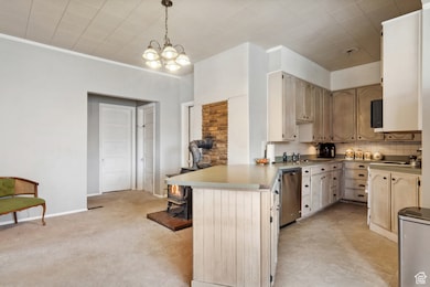 Kitchen featuring a peninsula, hanging light fixtures, backsplash, stainless steel appliances, and crown molding