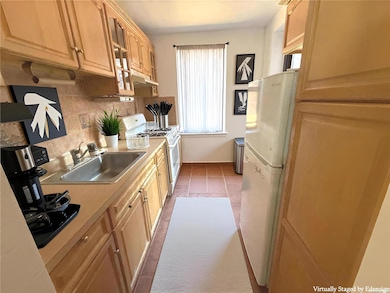Kitchen with white appliances, light countertops, tasteful backsplash, dark tile patterned flooring, and under cabinet range hood