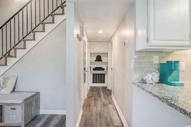 Hallway featuring dark wood-style flooring, a textured ceiling, and stairway