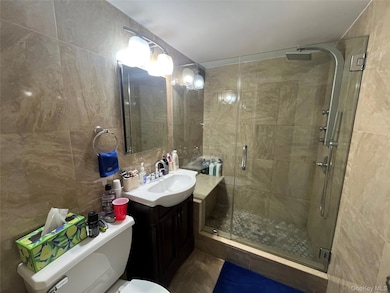 Bathroom featuring tile walls, a shower stall, vanity, and decorative backsplash