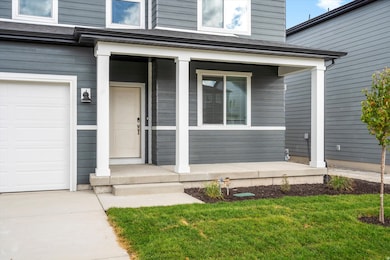 Property entrance featuring covered porch, a garage, and a yard