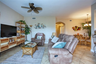 Living room with arched walkways, a ceiling fan, a chandelier, and tile patterned floors