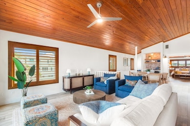 Living room with vaulted ceiling, wood finished floors, wood ceiling, ceiling fan, and ornamental molding