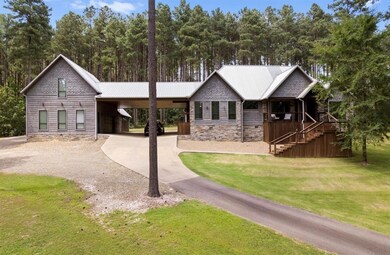 View of front of property with an attached carport, stone siding, driveway, a front lawn, and a metal roof