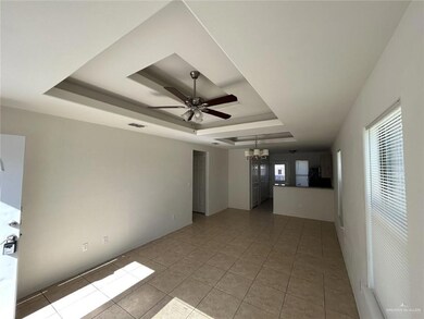 Spare room with a tray ceiling, light tile patterned floors, ceiling fan, and a chandelier