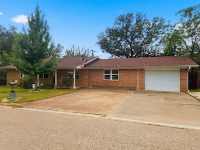 Ranch-style house featuring brick siding, driveway, an attached garage, a front lawn, and covered porch