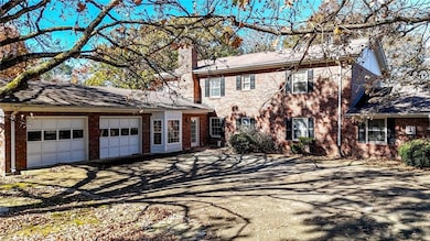 Colonial inspired home featuring a chimney, brick siding, driveway, and an attached garage
