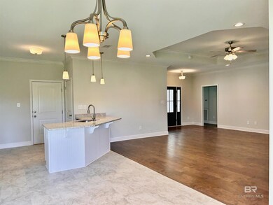 Kitchen featuring light wood-type flooring, pendant lighting, ceiling fan with notable chandelier, crown molding, and sink