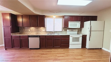 Kitchen with sink, white appliances, backsplash, a