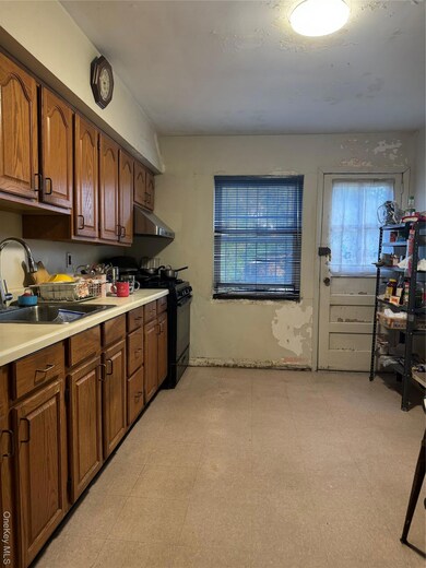 Kitchen featuring light countertops, light floors, range, brown cabinetry, and extractor fan