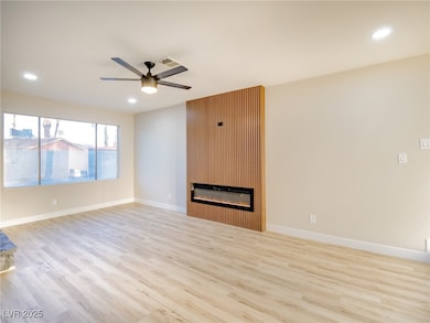 Unfurnished living room with light wood finished floors, a large fireplace, recessed lighting, and ceiling fan