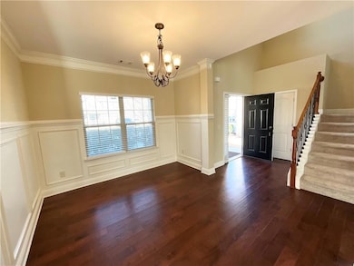 Unfurnished dining area with a chandelier, dark wo