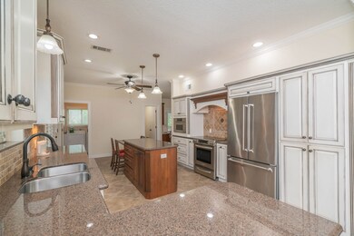 Continue directly into this beautifully updated island kitchen with granite countertops, a mosaic Travertine tile backsplash, and custom inked cabinetry with undercabinet lighting and conveniences that include a pull out spice drawer and concealed trash receptacle.