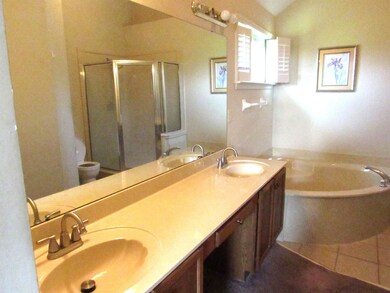 Full bath featuring a stall shower, a garden tub, double vanity, and toilet