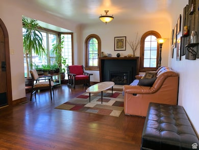 Living room with a glass covered fireplace, wood finished floors, and arched walkways
