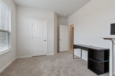 Secondary bedroom used as a study features carpet 
