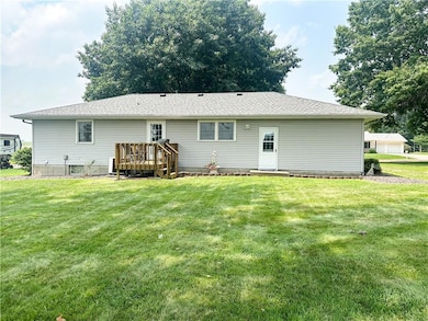 Back of property featuring a deck, a shingled roof, and a lawn