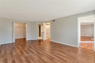 Unfurnished bedroom with wood finished floors, a spacious closet, a textured ceiling, and ensuite bathroom