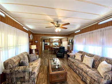 Living room with healthy amount of natural light, dark wood-type flooring, wooden walls, and a ceiling fan