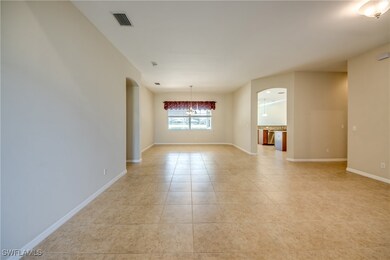 Empty room featuring arched walkways, light tile p