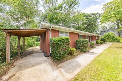 View of side of home featuring brick siding, concrete driveway, an attached carport, and a yard