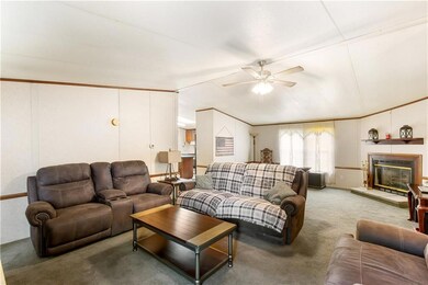 Living area featuring lofted ceiling, ceiling fan, carpet floors, and a glass covered fireplace