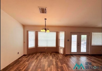 Unfurnished dining area featuring dark wood-style floors, a chandelier, and french doors