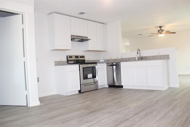 Kitchen with light hardwood / wood-style flooring, stainless steel appliances, ceiling fan, custom range hood, and white cabinets