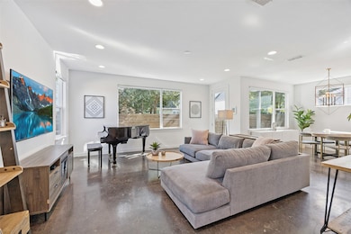 Living area featuring finished concrete floors, recessed lighting, and a chandelier
