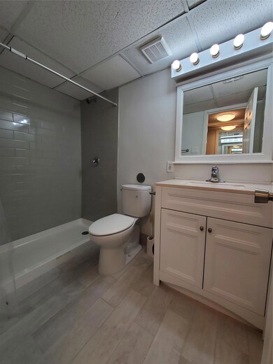 Full bathroom featuring a tile shower, toilet, va